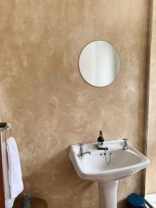 La salle de bains est pourvue d'un lavabo blanc et d'un miroir. dans l'établissement Sweet & Simple Beach Cottage, à Jeffreys Bay