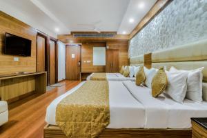 a bedroom with two beds and a flat screen tv at Hotel Kalka Royal in Katra