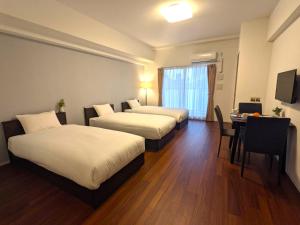 a hotel room with two beds and a table at ESLEAD HOTEL Namba Ebisu West in Osaka