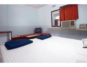 een slaapkamer met een groot wit bed met blauwe kussens bij Hotel Dharamlok,Agra in Agra