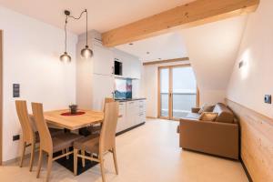 cocina y comedor con mesa de madera y sillas en Planerhof Apartment Edelweiss, en Funes