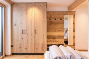 a bedroom with wooden walls and white furniture at Planerhof Apartment Edelweiss in Funes