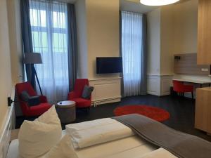 ein Hotelzimmer mit einem Bett und Stühlen sowie einem Schreibtisch in der Unterkunft Schloss Beuggen in Rheinfelden