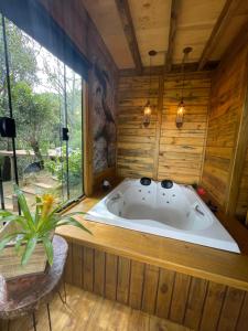 uma banheira de hidromassagem num quarto com paredes de madeira em Recanto Lira II em Monte Verde