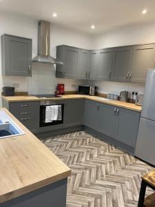 una cucina con armadi grigi e un tappeto sul pavimento di House In Padfield a Tintwistle
