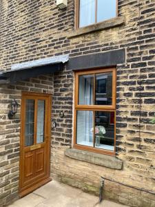 a brick building with a door and a window at House In Padfield in Tintwistle