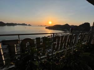 einen Sonnenuntergang über einem Wasserkörper mit einem Zaun in der Unterkunft Cat Ba Bay Vision Hotel in Cát Bà