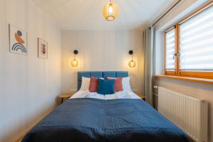 a bedroom with a blue bed and a window at Apartamenty Ogrodowa w centrum Ustronia - Dream Apart in Ustroń