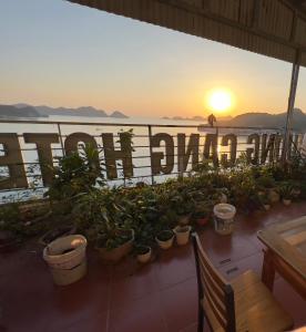 un restaurante con macetas y vistas a la puesta de sol. en Huong Cang Sea View Hotel, en Cat Ba