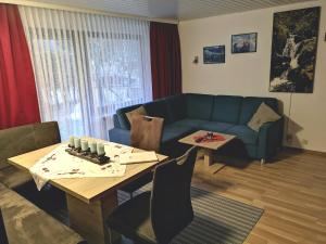 ein Wohnzimmer mit einem blauen Sofa und einem Tisch in der Unterkunft A6 Albmatte-FEWO Sauna, Hallenbad Außenbecken Massagen nebenan in Menzenschwand-Hinterdorf