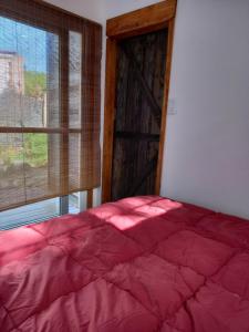 a bedroom with a red bed and a window at Aguaymanto in Cuchilla Alta