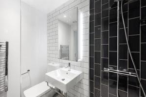 a black and white bathroom with a sink and a mirror at Cave Apartments in London