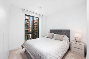 a white bedroom with a bed and a window at Cave Apartments in London
