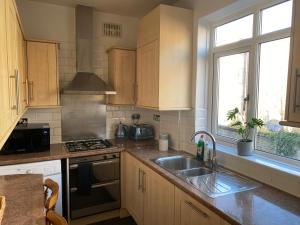 a kitchen with a sink and a stove at Lovely 3 bedroom maisonette with private roof terrace in Hammersmith in London