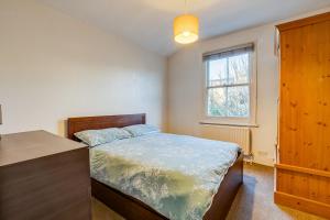 a bedroom with a bed and a dresser and a window at Lovely place, perfect for family and business travellers ideally located between the commons in London