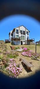 a house with a bunch of flowers in front of it at Ancora in Punta Del Diablo