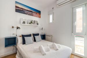 a white bedroom with a large white bed with pillows at BNBHolder Bright Plaza España in Madrid