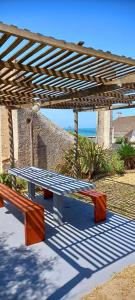 un banco de picnic bajo una pérgola de madera en Ancora en Punta del Diablo