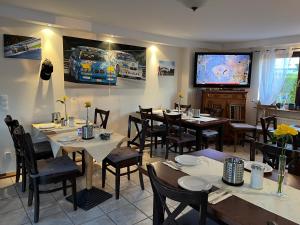 een restaurant met tafels en stoelen en een flatscreen-tv bij Landhaus Balkhausen in Nürburg