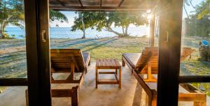 a porch with tables and chairs and a view of the ocean at Lazy Day The Resort in Ko Mak