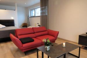 a living room with a red couch and a table at Schatzkiste Schatzkiste 1 EG in Uhldingen-Mühlhofen