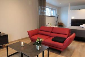 a living room with a red couch and a bed at Schatzkiste Schatzkiste 2 EG in Uhldingen-Mühlhofen