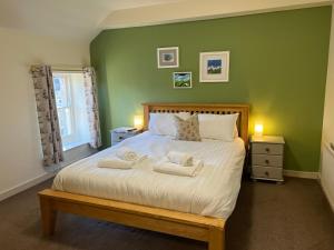 a green bedroom with a bed with towels on it at The Beresford Arms in Morpeth