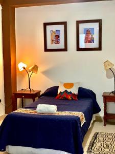 1 dormitorio con 1 cama azul y 2 lámparas en Ayllu en Salta