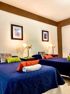 2 camas en una habitación con sábanas azules y almohadas de color naranja en Ayllu en Salta
