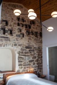 1 dormitorio con una pared de piedra, cama y luces en Casa Sanui. Apartaments turístics rurals, en Estorm