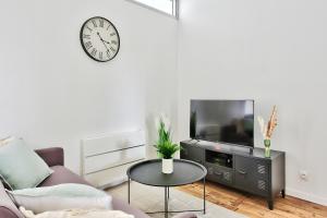 a living room with a couch and a tv and a table at Appartement Le Cocon Lyonnais in Villeurbanne