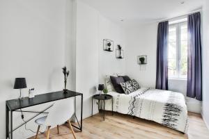 Habitación blanca con cama y escritorio en Appartement Le Cocon Lyonnais, en Villeurbanne
