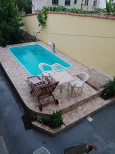 a patio with a table and chairs next to a swimming pool at Pousada Clave de Sol in Conservatória