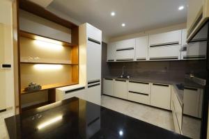 a kitchen with white cabinets and a black counter top at Woodlands Apartment- Fully furnished Luxury Apt in Jodhpur