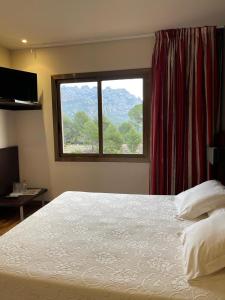 um quarto com uma cama grande e uma janela em Hotel Bruc em El Bruc