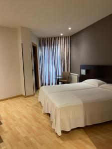 a bedroom with a large white bed and a table at Hotel Bruc in El Bruc