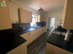 a kitchen with white cabinets and black counter tops at Aire Street -TSAC in Middlesbrough