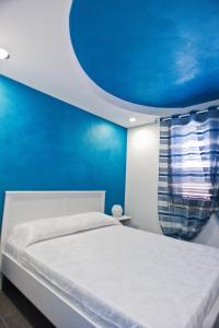a bedroom with a white bed and a blue wall at B&B Lido Esperando Sciacca in Sciacca