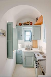 a small kitchen with blue cabinets and a sink at Zoe Aegeas Traditional houses in Oia