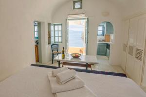 Habitación blanca grande con cama y mesa en Zoe Aegeas Traditional houses, en Oia