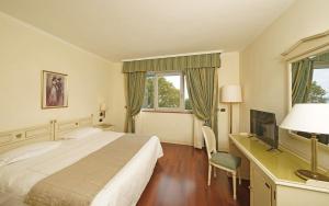 a bedroom with a bed and a desk and a television at Hotel Savoy Palace in Gardone Riviera