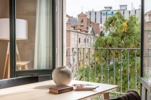 una mesa con un jarrón en la parte superior de una ventana en Líbere Madrid Palacio Real en Madrid