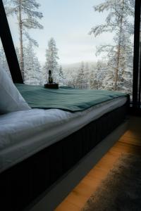 a bed in a room with a window with trees at Salla Wilderness Lodges in Salla