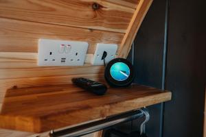 uno specchio e un telecomando seduti su una mensola in legno di North Coast 500 Pods ad Achmelvich