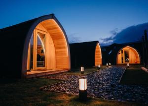 a row of wooden buildings with candles in the grass at North Coast 500 Pods in Achmelvich
