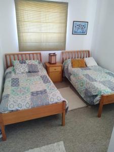 a bedroom with two beds and a night stand at Dpto Cau Cau Horcón in Puchuncaví