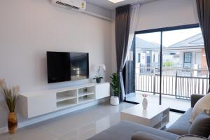 a living room with a television on a white wall at LARGE & QUIET 3bd Home with Security & Pool in Ubon Ratchathani
