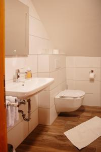 a white bathroom with a sink and a toilet at Gasthof Schattleitner in Brückl