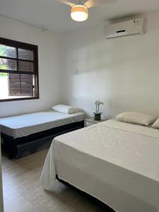2 camas en una habitación blanca con ventana en Apartamento Aldeia da Praia, en Porto Seguro
