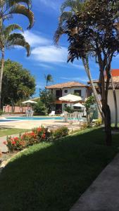 un edificio con sombrillas y flores en un parque en Apartamento Aldeia da Praia, en Porto Seguro